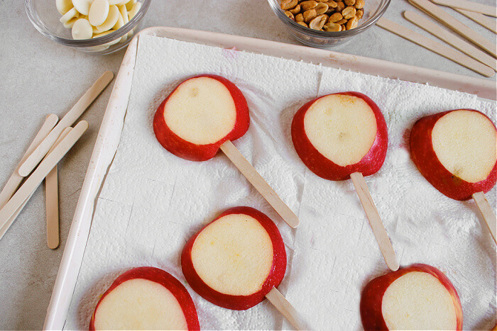 sliced apples with sticks in them laying on a paper towel