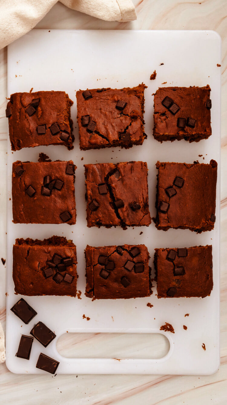 nine pumpkin chocolate brownies cut into serving pieces on a white cutting board