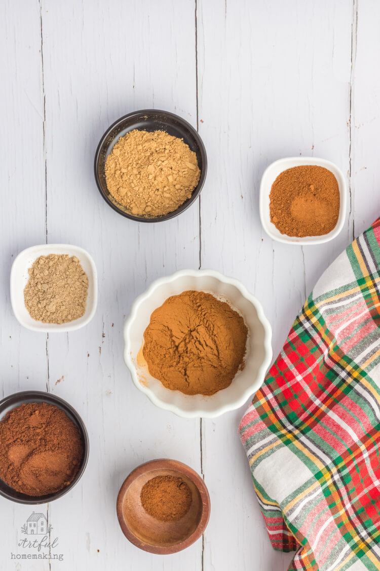 ingredients in small bowls on a white wood table next to a plaid towel