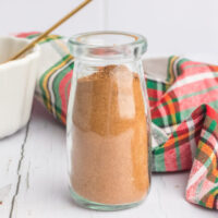 Christmas spice mix in a glass jar on a white wooden table