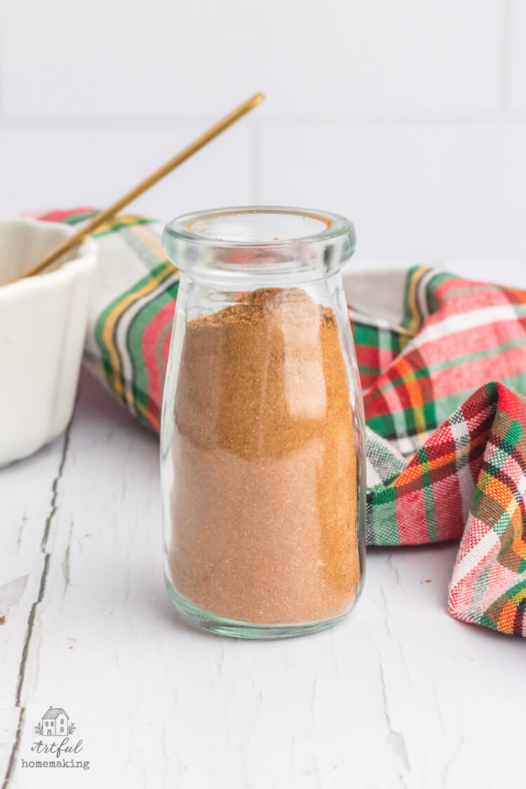 Christmas spice mix in a glass jar on a white wooden table