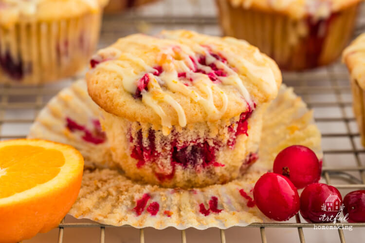 cranberry orange muffins with orange slice and cranberries on a wire rack