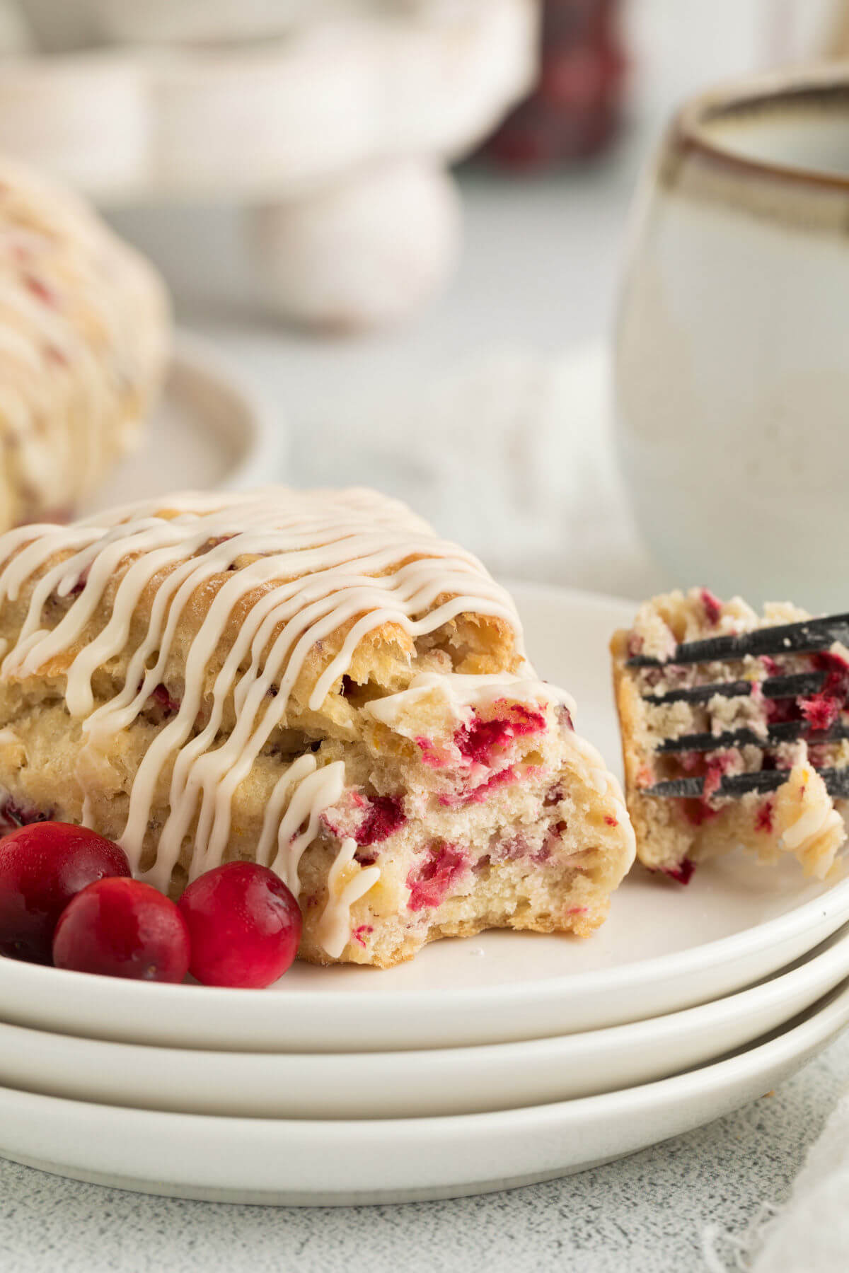 sourdough cranberry orange scones on a white plate, with a fork cutting off a piece