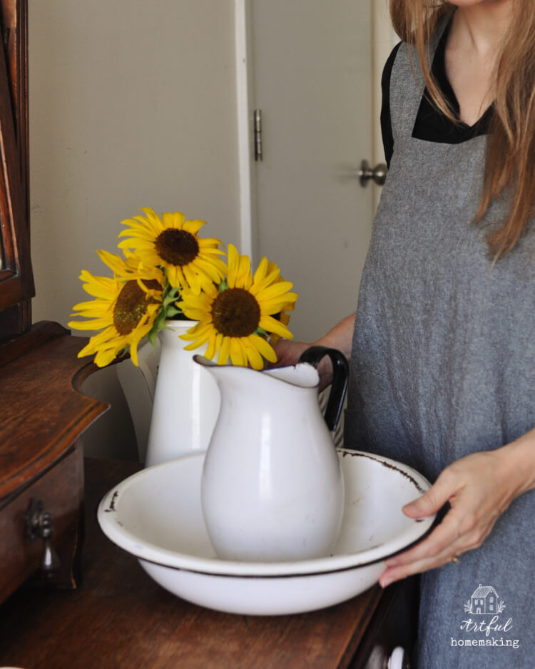 woman in linen apron next to sunflowers in a pitcher