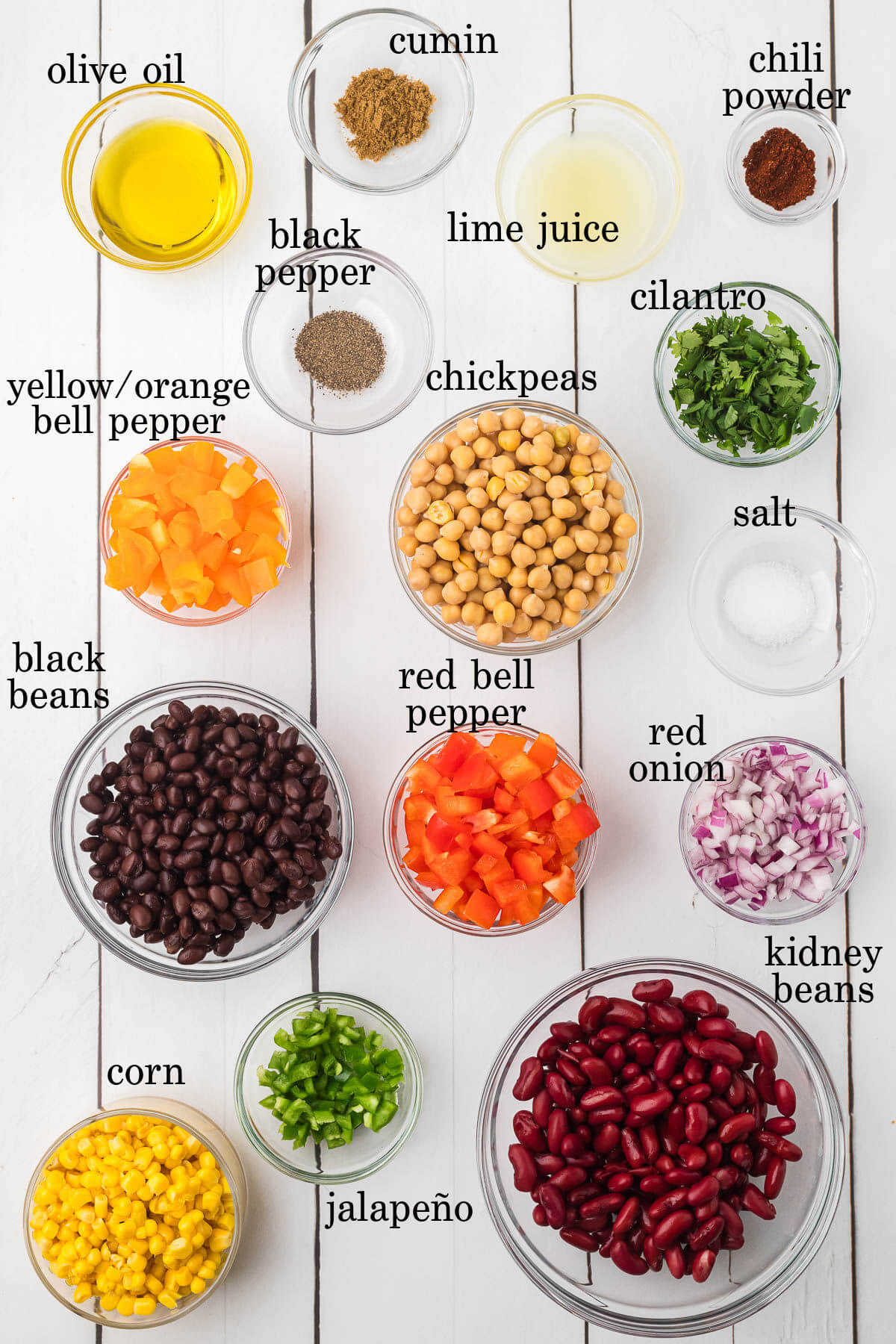Dense bean salad ingredients in small bowls with text overlay labeling each ingredient,