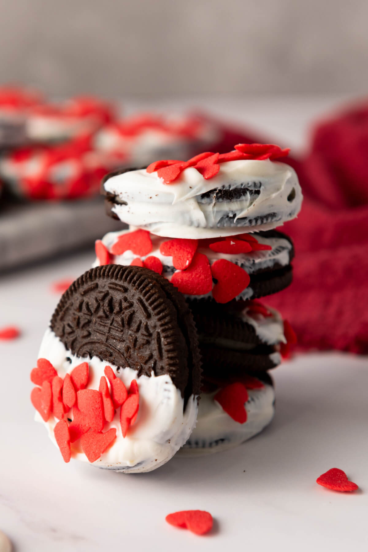 a pile of Oreos dipped in white chocolate and heart sprinkles for Valentine's Day