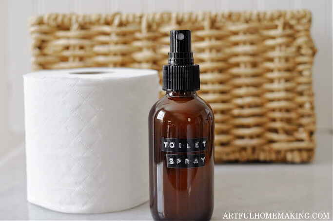 natural toilet spray in amber glass bottle with roll of toilet paper