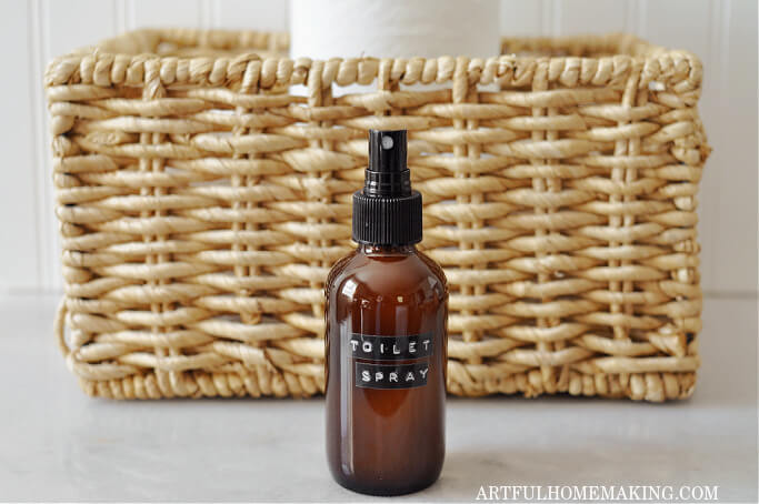 diy poo pourri spray in amber bottle with basket and toilet paper