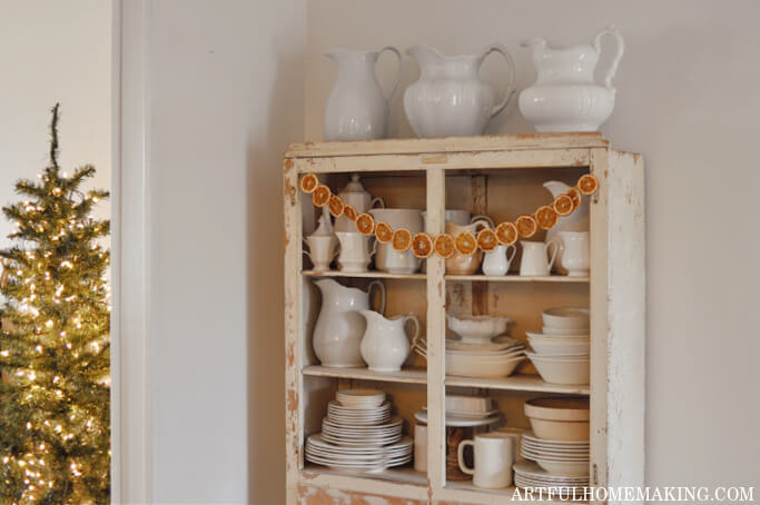 Christmas tree with lights and china hutch with orange garland