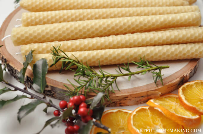 beeswax candles, dried orange slices, and holly on a table