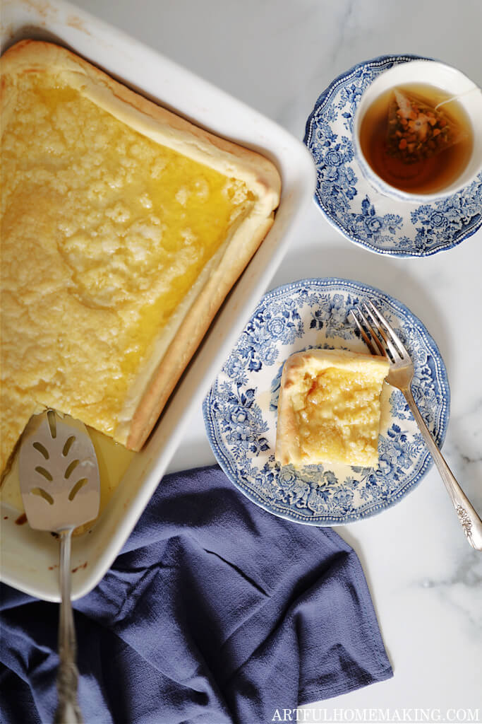 dutch puff pancake in white baking dish with a piece on a plate and a cup of tea