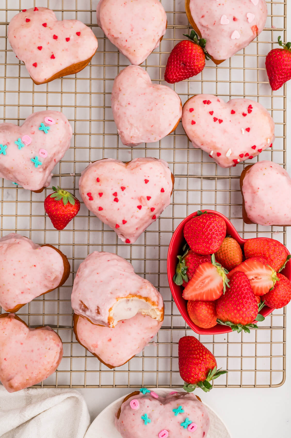 wire cooling rack with strawberry donuts with strawberry glaze and a bowl of strawberries