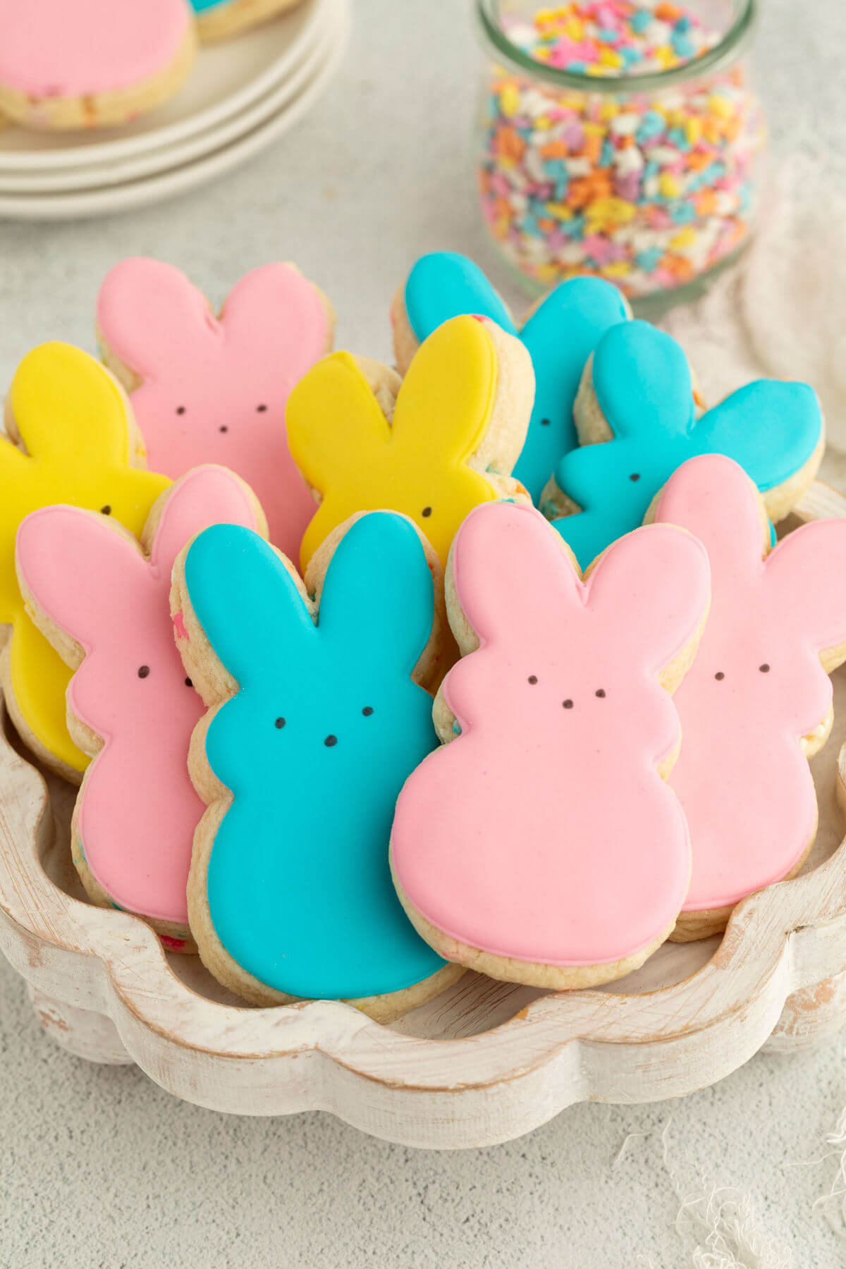 a pile of pastel frosted bunny-shaped Easter cookies in a white bowl