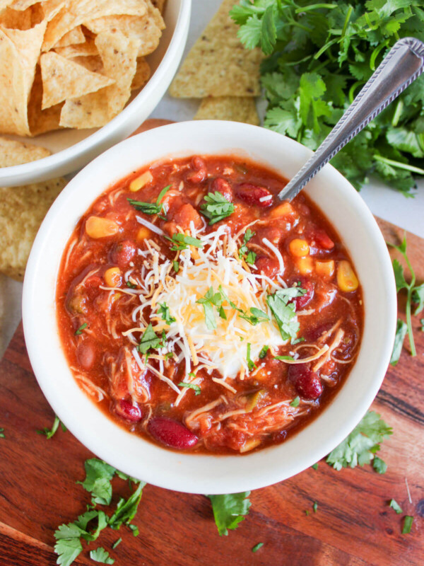 Crockpot taco chicken chili in a bowl with cheese and parsley garnish.