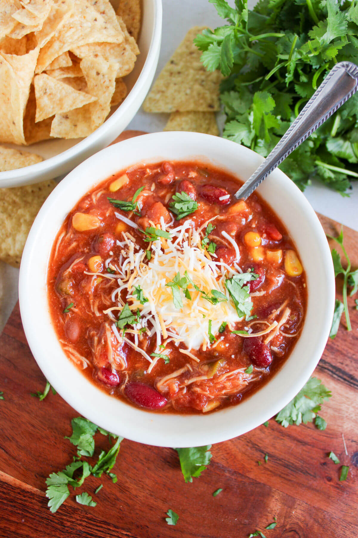 Crockpot taco chicken chili in a bowl with cheese and parsley garnish.