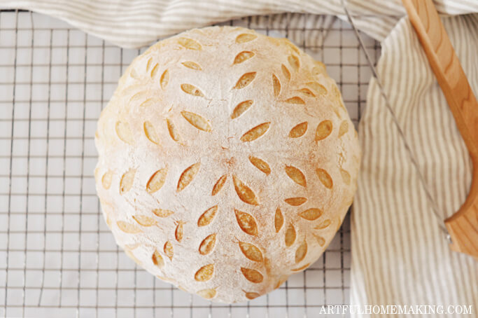 sourdough bread on a cooling rack with a wooden knife