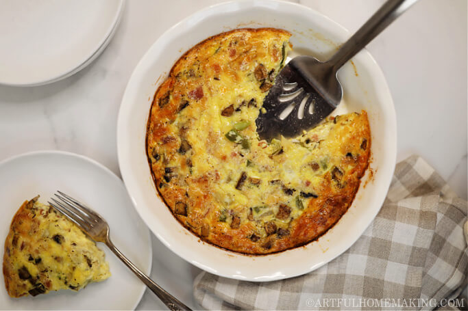 quiche in a white pie dish with a pie serving spoon, and a piece of quiche on a plate
