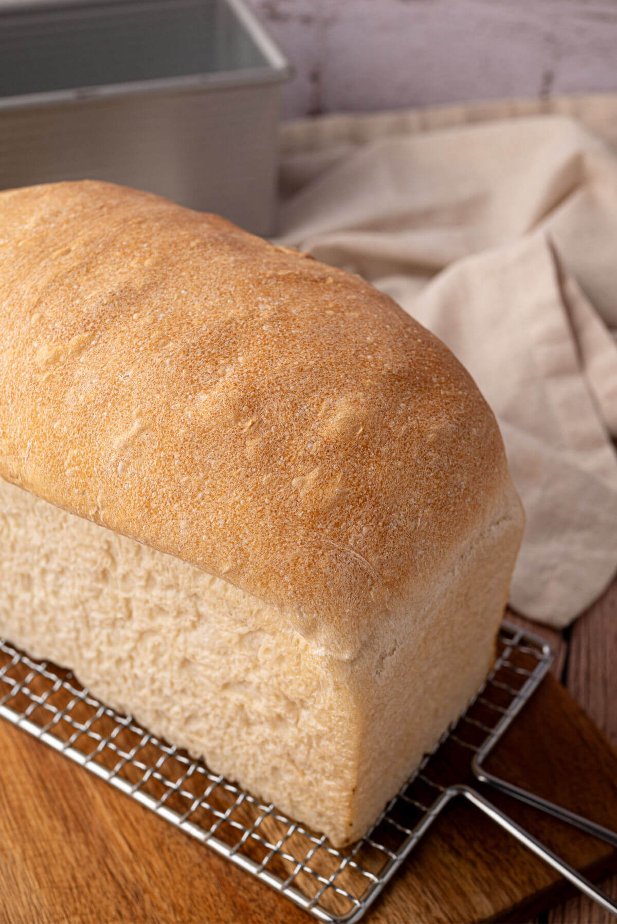 Sourdough sandwich bread loaf on a wire rack.