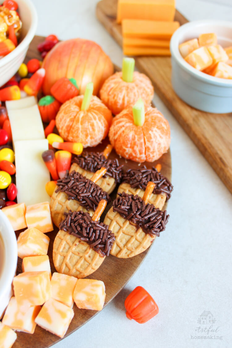 mandarin orange "pumpkins," nutter butter "acorns," and cheese slices on a wooden tray