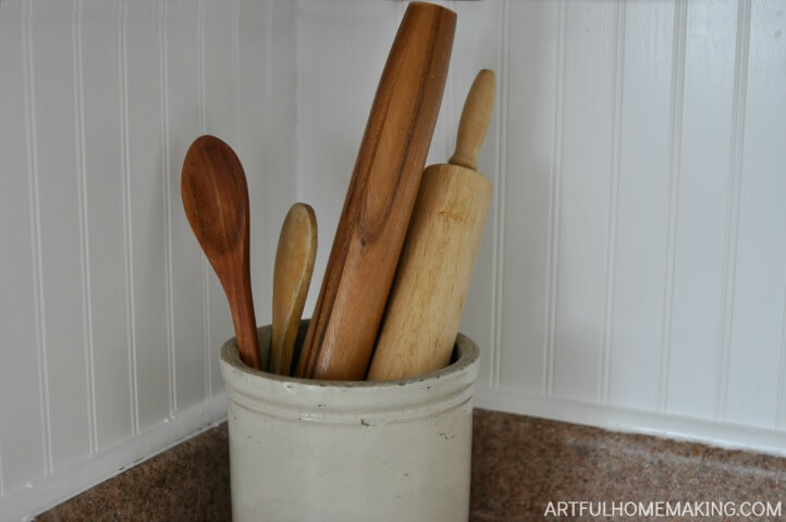 old crock with rolling pins and wooden spoons in front of bead board kitchen backsplash