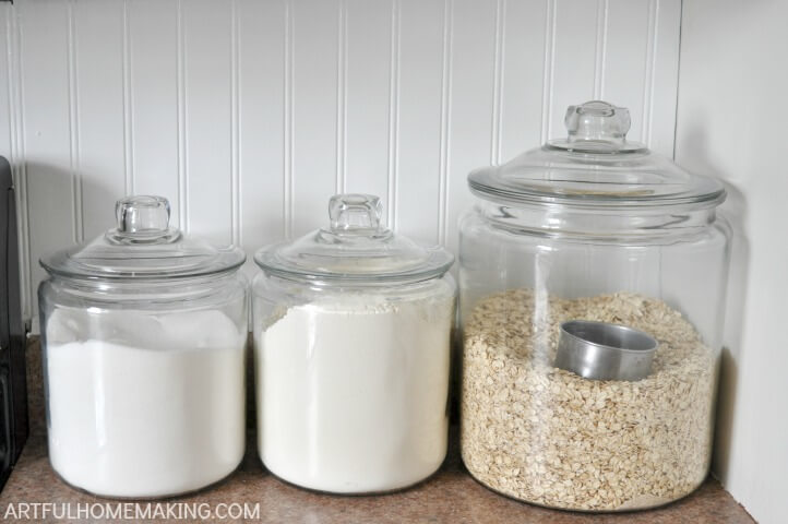 glass canisters on a kitchen counter with sugar, flour, and oats