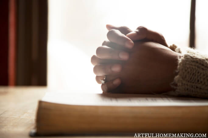 hands praying on bible