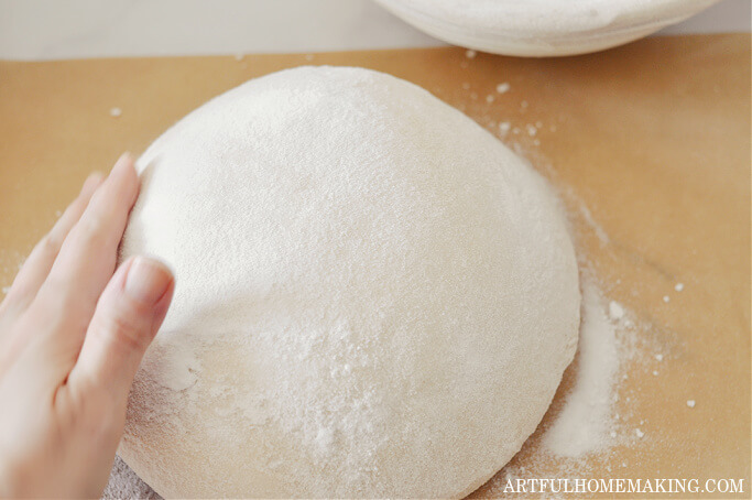 smoothing flour on top of sourdough loaf