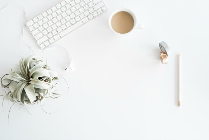 white desk with coffee, keyboard, plant