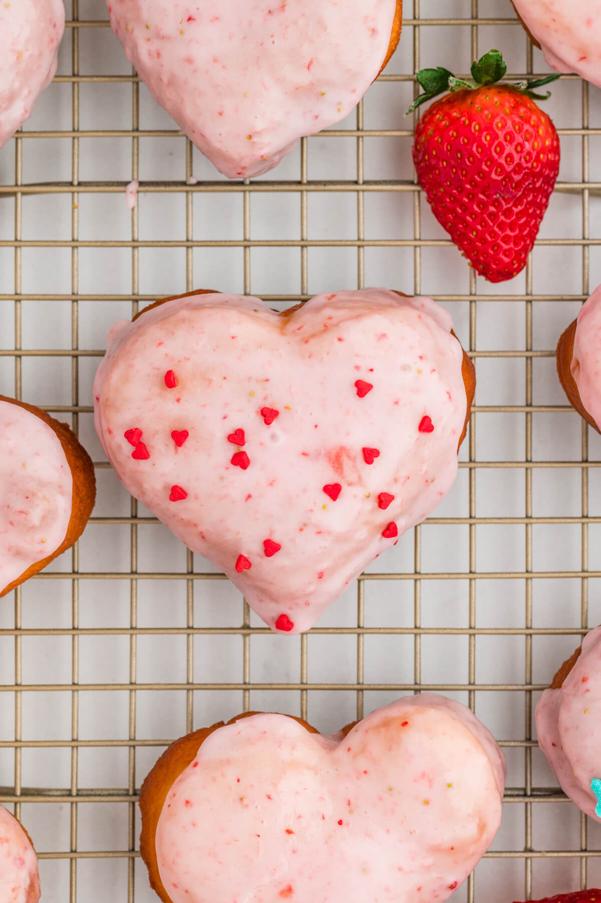 strawberry heart shaped donuts with strawberry glaze on a metal cooling rack