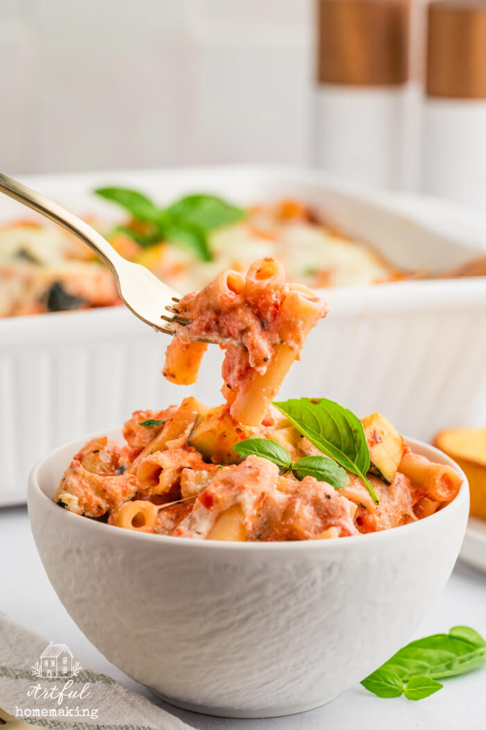 meatless baked ziti in a white bowl with a gold fork holding up some of the pasta