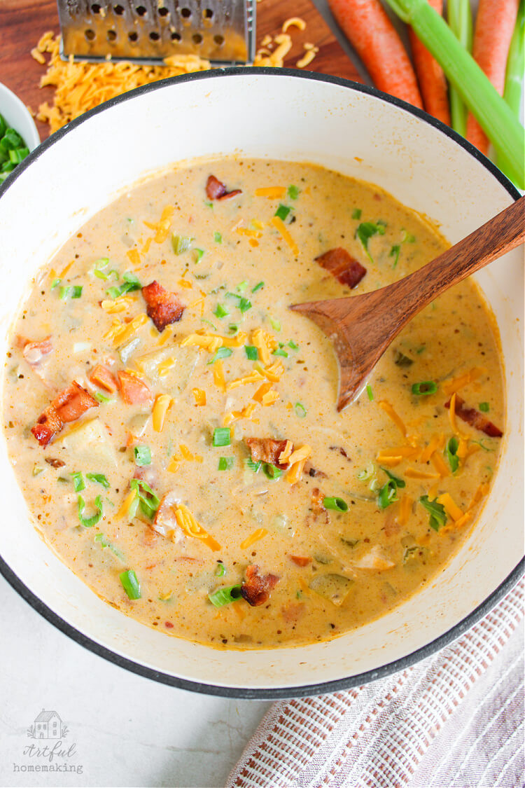 a white bowl filled with homemade chicken potato soup with a wooden spoon