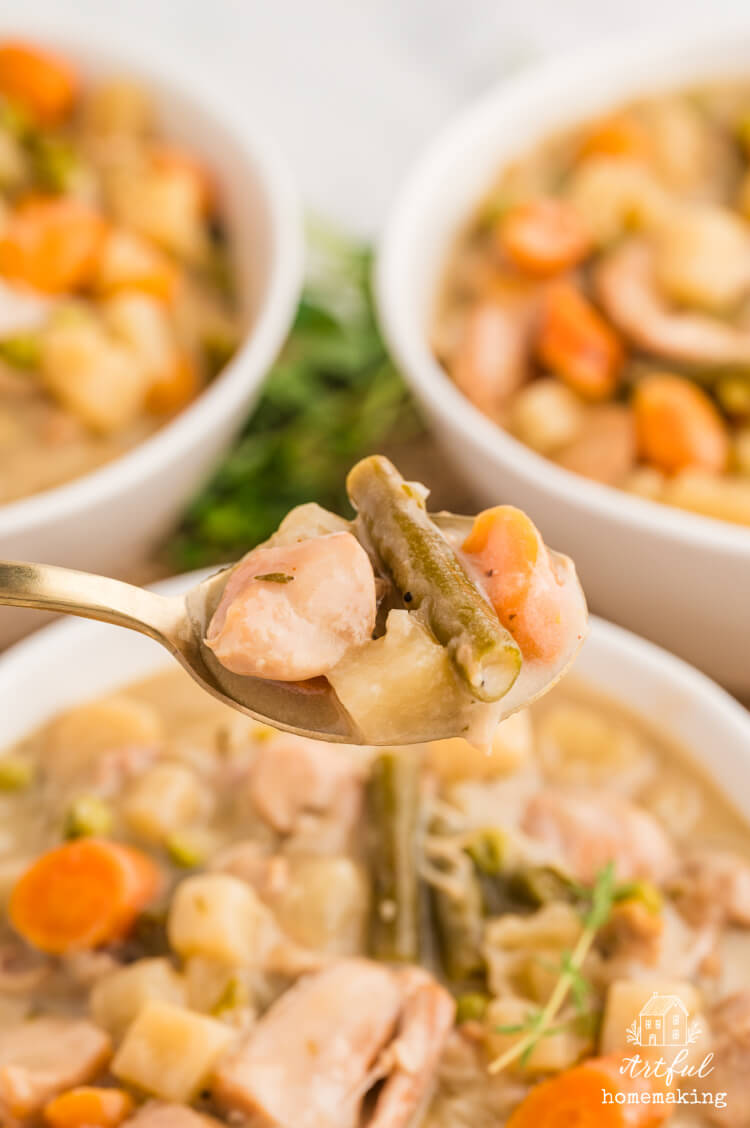 a gold spoon holds up a bite of stew