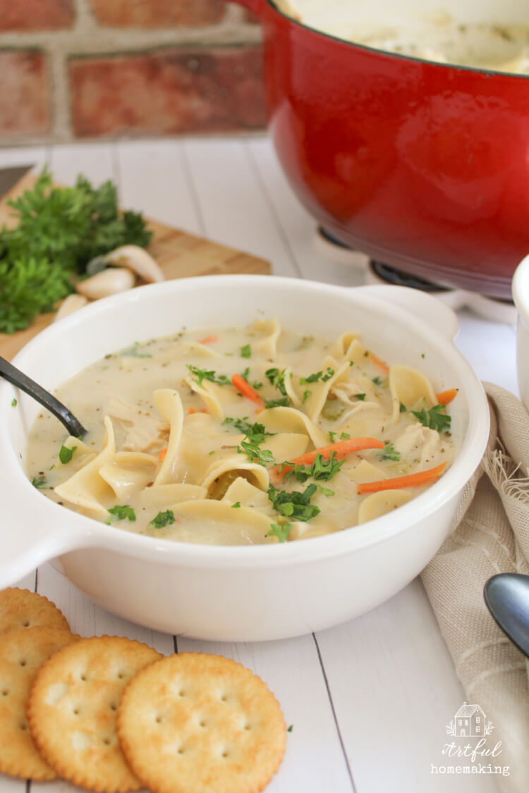 a white bowl filled with creamy chicken noodle soup
