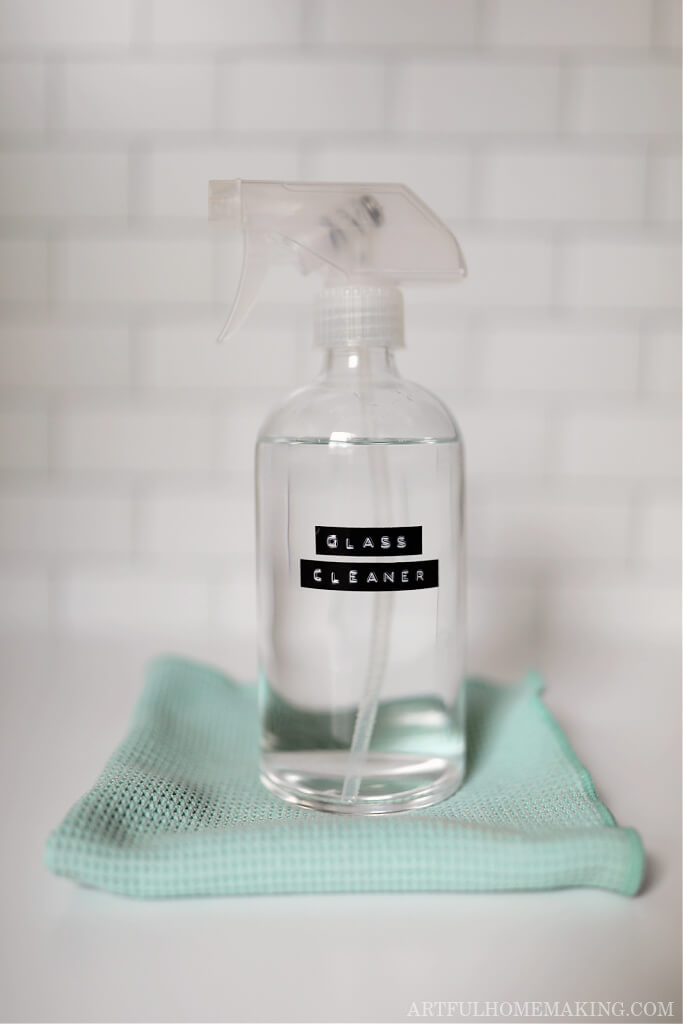 glass cleaner in a glass spray bottle on a marble countertop with a cleaning cloth
