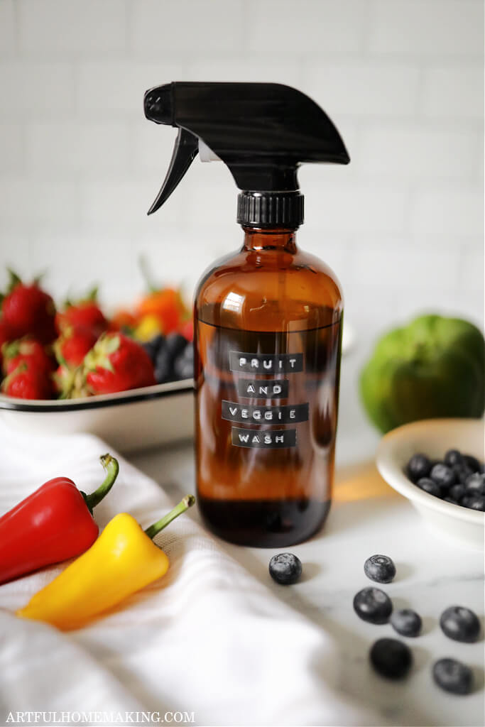 amber spray bottle with a label that says fruit and veggie wash spray surrounded by fruit and vegetables