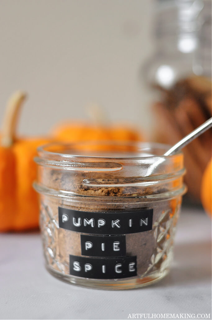 homemade pumpkin pie spice in a jar surrounded by pumpkins and cinnamon sticks