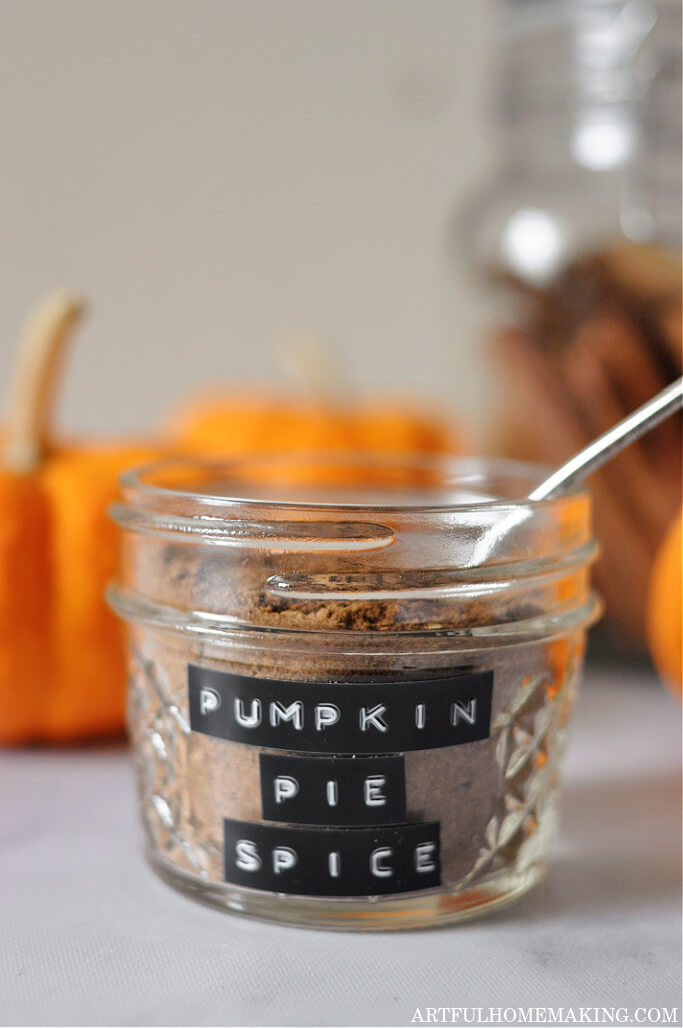 homemade pumpkin pie spice in a jar surrounded by pumpkins and cinnamon sticks