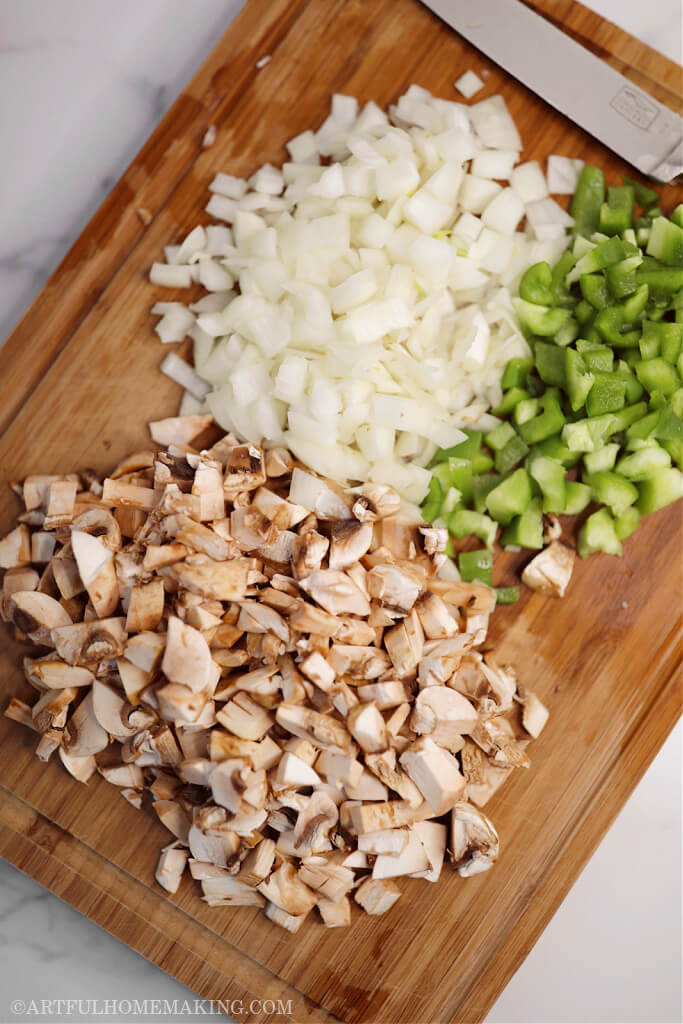 diced onions, green bell peppers, and mushrooms on a wooden cutting board