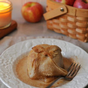 sourdough apple dumpling on a plate with syrup around it and a fork