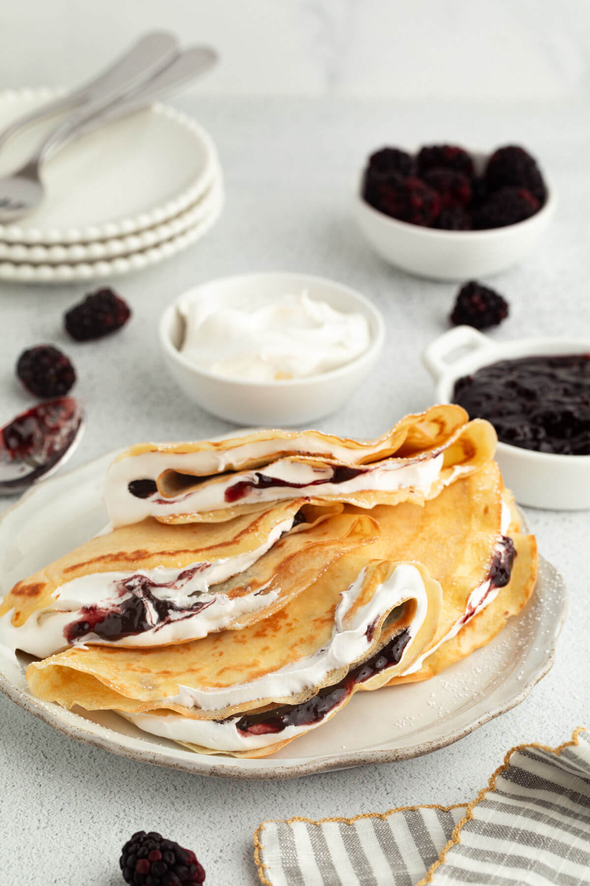Sourdough crepes on a plate and filled with berries and whipped cream.