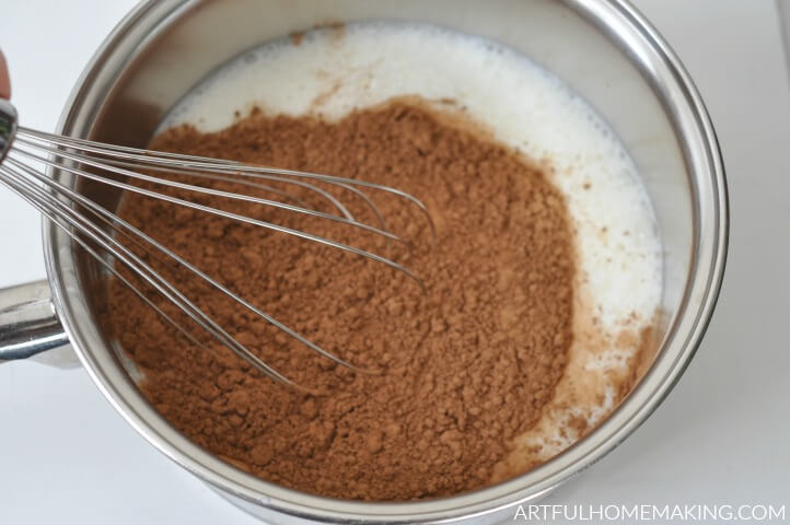 Whisking cocoa powder into milk in the saucepan.