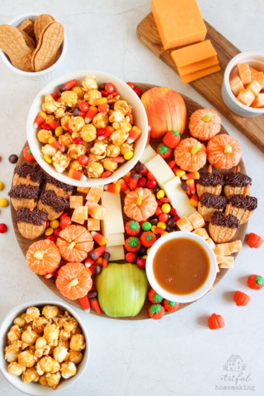fall dessert charcuterie board with apples, caramel corn, and candy