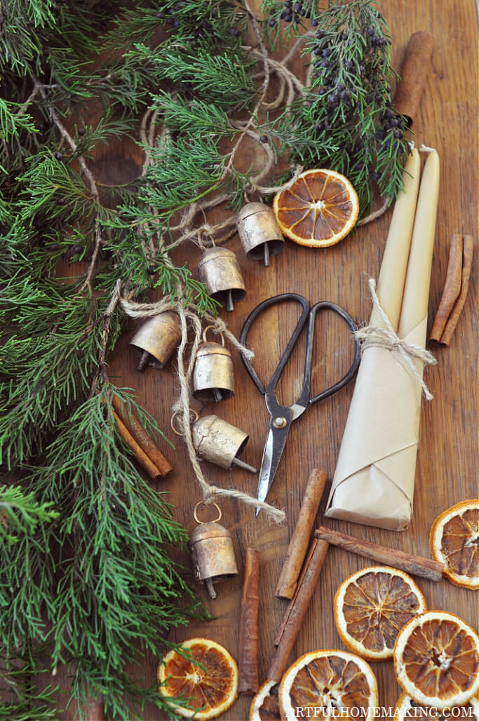 dried orange slices with greenery, brass bells, and beeswax candles