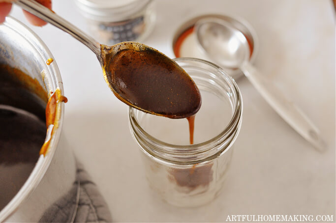 pumpkin spice coffee syrup on a spoon dripping into a glass jar for storage