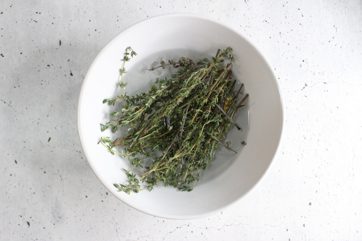 white bowl with fresh thyme sprigs and water in it