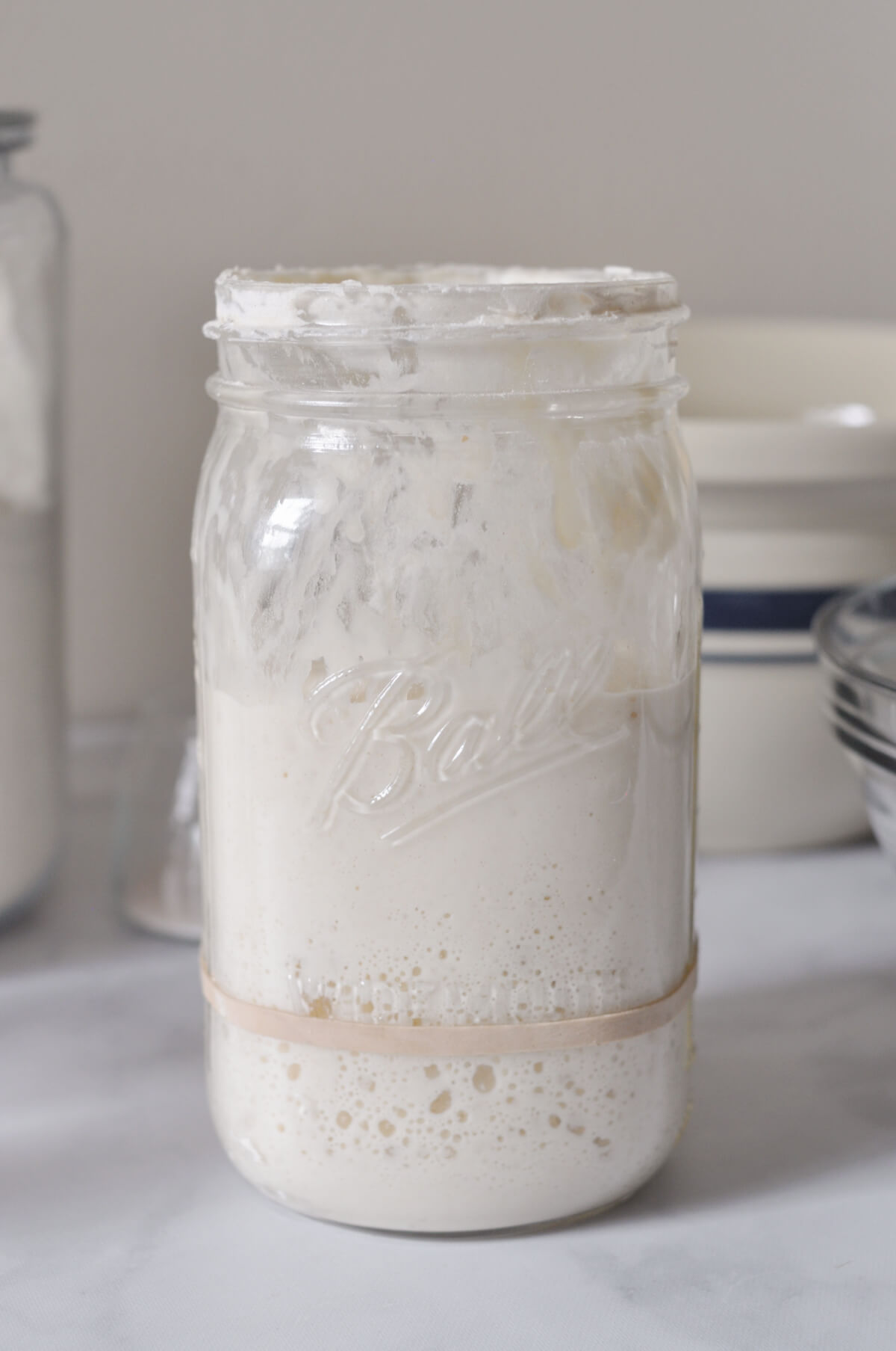 Jar of sourdough starter with bubbles showing starter has tripled and is ready to use.