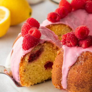Lemon raspberry bundt cake with one slice being taken out.
