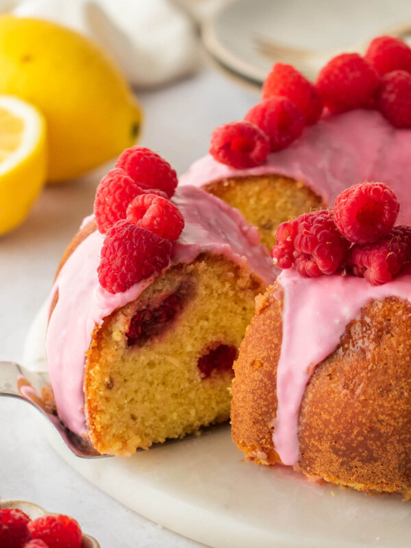 Lemon raspberry bundt cake with one slice being taken out.