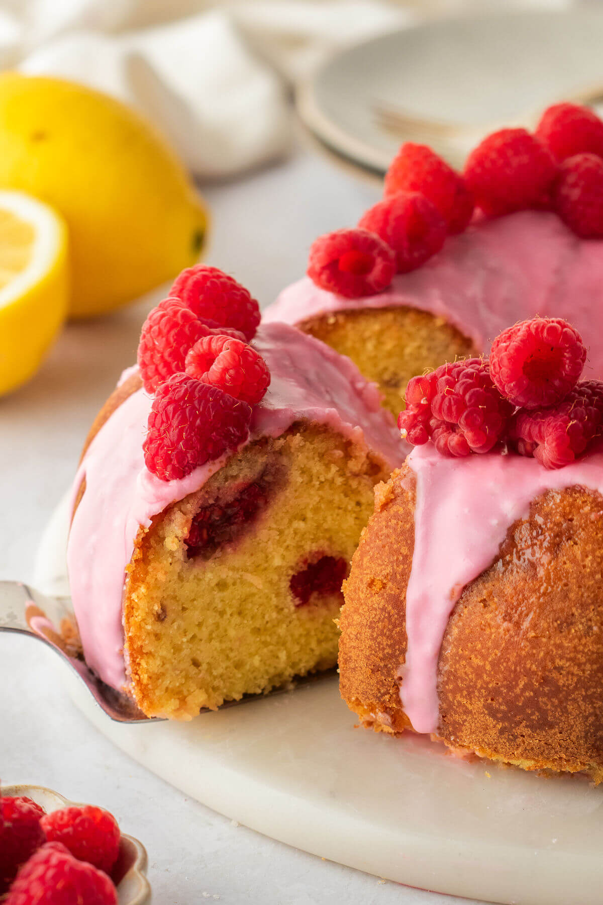 Lemon raspberry bundt cake with one slice being taken out.