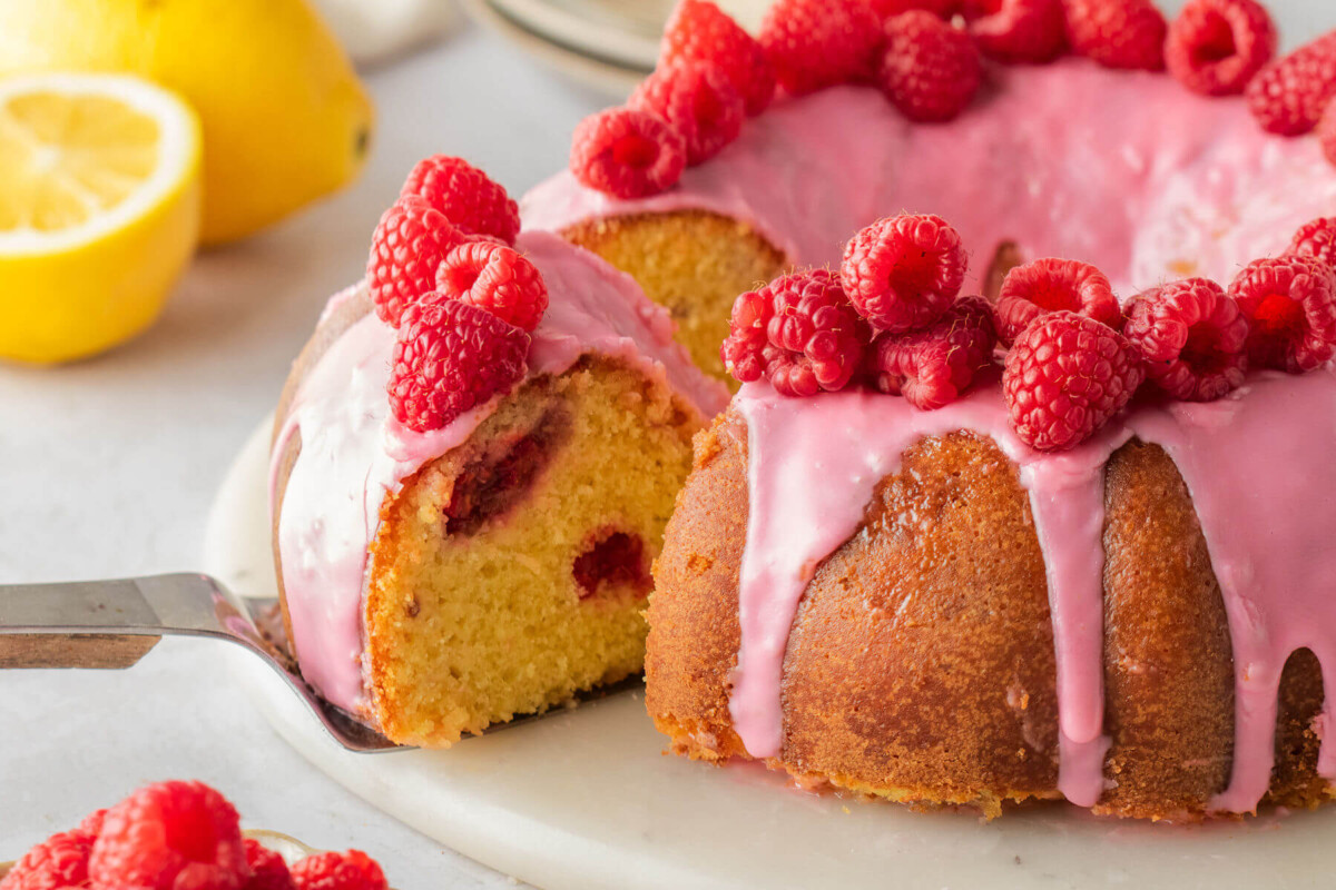 Lemon raspberry bundt cake with a slice being cut out for serving.